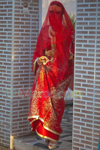 Une mariée en caftan rouge descend un escalier
