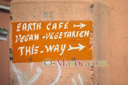 Sur les murs de la médina de Marrakech, un panneau vers un restaurant végétarien