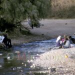 Au bord de la rivière, des femmes se parlent pendant que le linge sèche sur un arbre