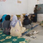 Des femmes assises par terre apprennent à lire et écrire l'arabe