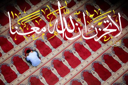 Un homme en train de prier sur un tapis de prière avec une calligraphie religieuse