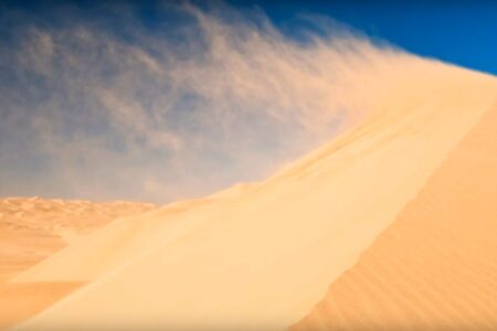 Le vent fait voler le sable en haut d'une dune