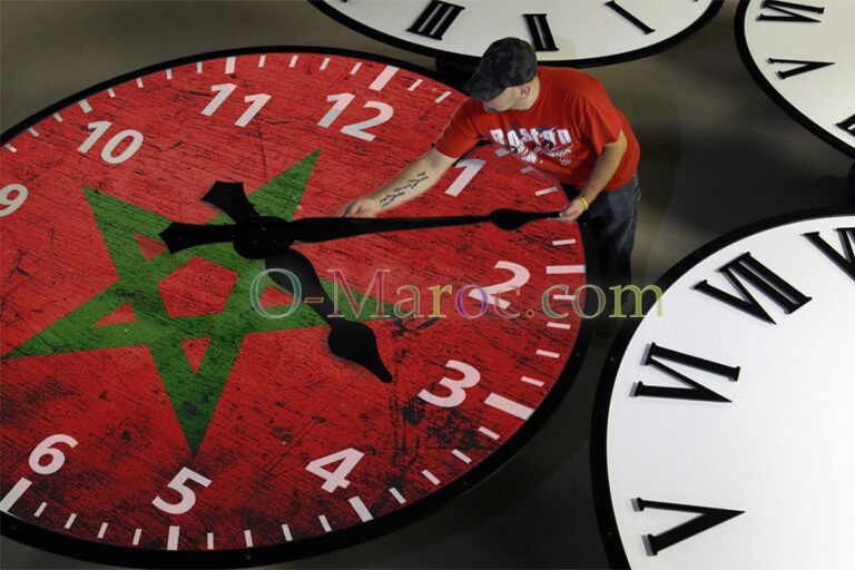 Un homme déplace les aiguilles d'une horloge décorée du drapeau marocain