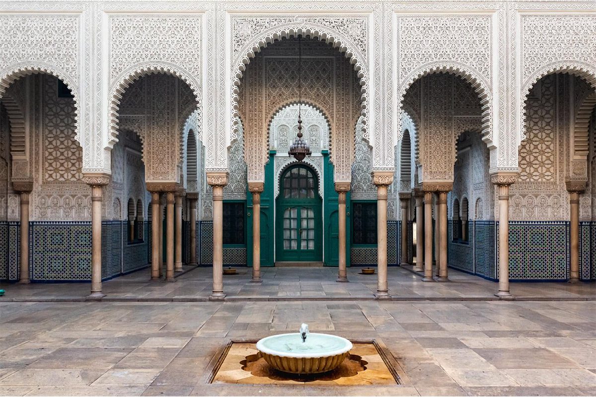 Cour intérieure de la Mahkama du Pacha avec sa fontaine, ses zelliges et ses arches ornées de stuc richement sculpté