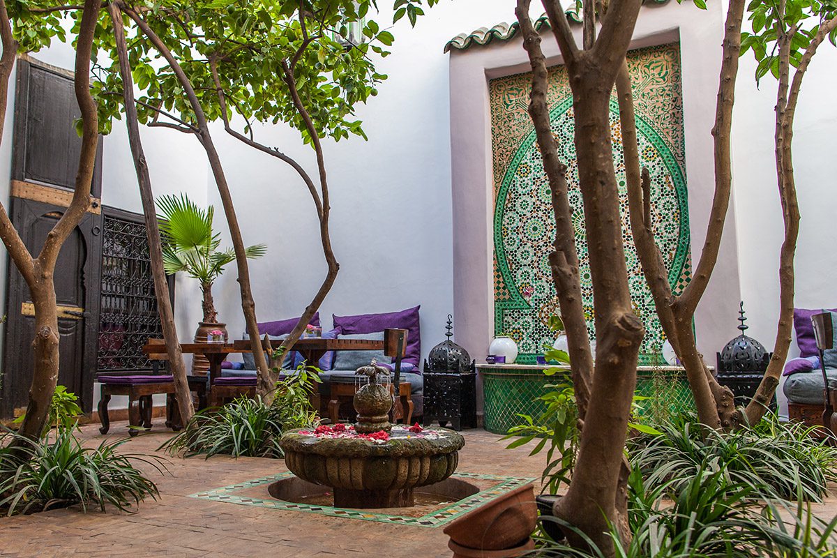 Cour de riad à Marrakech avec une fontaine centrale et des arbres
