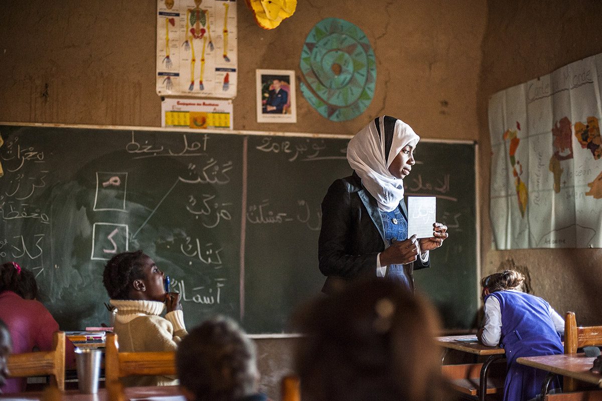 Une institutrice enseigne les lettres arabes à de jeunes enfants berbères