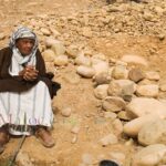 Sur une colline de pierre, un vieil homme en djellabah