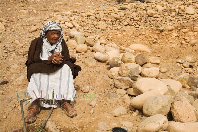 Sur une colline de pierre, un vieil homme en djellabah